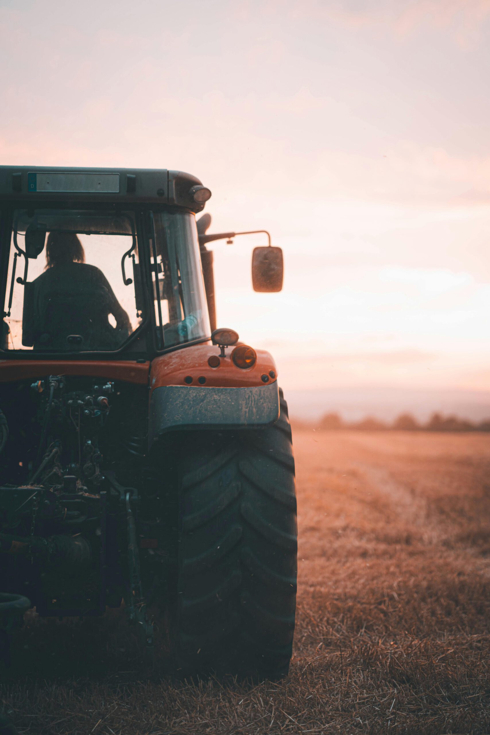 A tractor sits in an open field at sunset, showcasing agriculture's beauty.